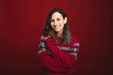 Portait of charming smiling young woman in red sweater looking confident at the camera