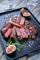 Traditional barbecue dry aged wagyu porterhouse steak sliced with fruit and spice as closeup on a modern design tray