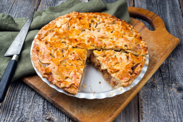 Traditioneller gedeckter Apfelkuchen angeboten als closeup in einer Backform auf einem alten...