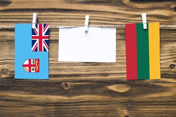 Hanging flags of Fiji and Lithuania attached to rope with clothes pins with copy space on white...