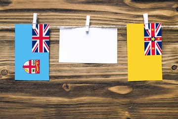 Hanging flags of Fiji and Niue attached to rope with clothes pins with copy space on white note...