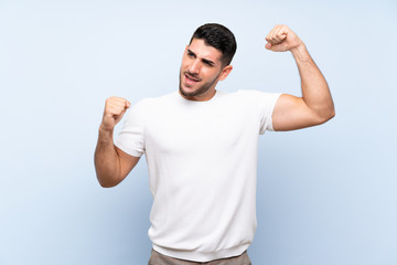 Caucasian handsome man over isolated blue background celebrating a victory