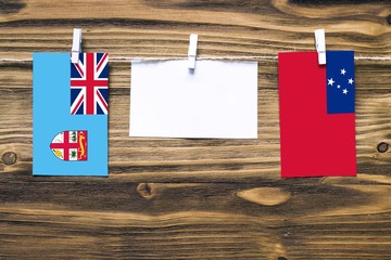 Hanging flags of Fiji and Samoa attached to rope with clothes pins with copy space on white note...