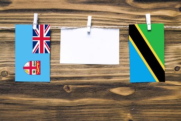 Hanging flags of Fiji and Tanzania attached to rope with clothes pins with copy space on white note...