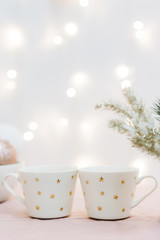 Fototapeta na wymiar Two cups for christmas cacao with marshmellous, golden stars, new year tree, scandinavian kitchen, festive background