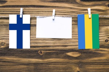 Hanging flags of Finland and Gabon attached to rope with clothes pins with copy space on white note...