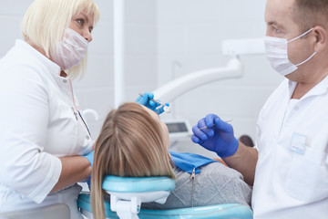 Obraz premium Doctor dentist treats teeth of a beautiful young girl patient. The girl on reception at the dentist. Doctor dentist treats tooth