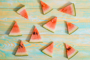 Slices of watermelon on old blue and yellow wooden background. Chopped watermelon. summer, harvest and vacation concept. Flat lay, top view.