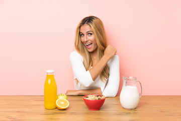 Young blonde woman having breakfast milk celebrating a victory