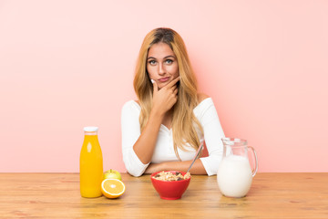 Young blonde woman having breakfast milk thinking an idea