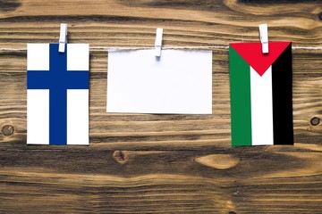 Hanging flags of Finland and Palestine attached to rope with clothes pins with copy space on white...