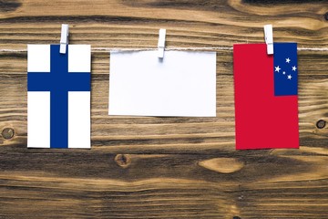 Hanging flags of Finland and Samoa attached to rope with clothes pins with copy space on white note...