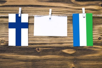 Hanging flags of Finland and Sierra Leone attached to rope with clothes pins with copy space on...
