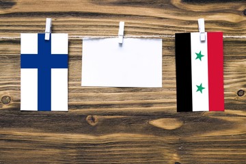 Hanging flags of Finland and Syria attached to rope with clothes pins with copy space on white note...