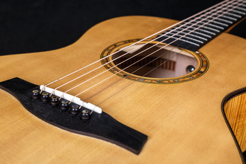 wood texture of lower deck of six strings acoustic guitar on black background. guitar shape