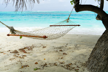 Empty hammock between palms trees at sandy beach