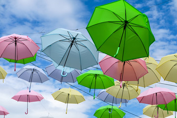Fototapeta na wymiar colorful fancy umbrella line decorate outdoor moving by wind on blue sky white cloud