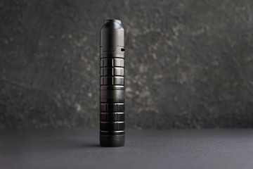 Vaping device mech mod electronic cigarette on black textured background. Modern vaporizer e-cig gadget to vape glycerin e-liquid. Free space for your text.     
