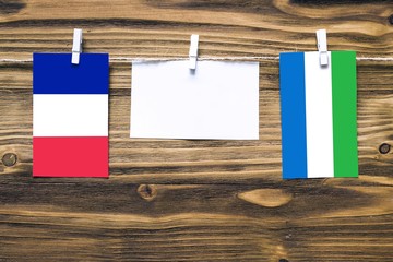 Hanging flags of France and Sierra Leone attached to rope with clothes pins with copy space on...