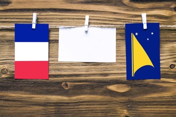 Hanging flags of France and Tokelau attached to rope with clothes pins with copy space on white...