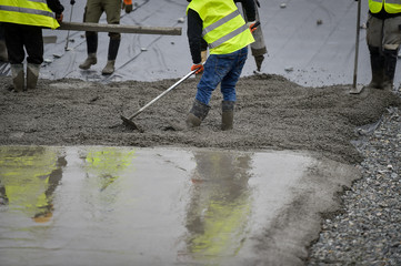 Detail with team of workers pouring concrete on a construction site.