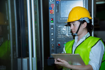 Young woman staff writing on clipboard while check machine. factory and SME concept .