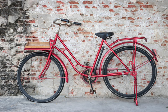 Red vintage bicycle parked in front of brick wall