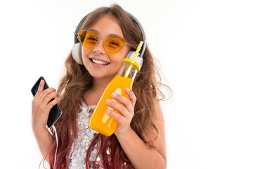 Smiling little girl listenes to music in smartphone