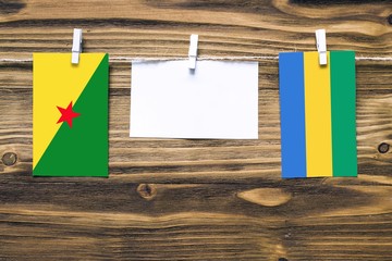Hanging flags of French Guiana and Gabon attached to rope with clothes pins with copy space on...