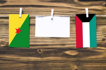 Hanging flags of French Guiana and Kuwait attached to rope with clothes pins with copy space on...