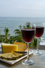 Red wine served in glasses with spanish cheese in lounge bar with sea view and palm trees