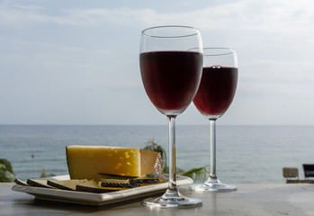 Red wine served in glasses with spanish cheese in lounge bar with sea view and palm trees