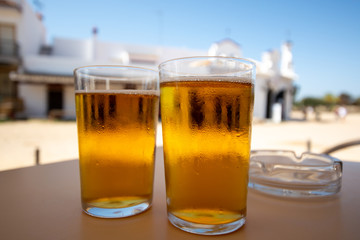 Cold amber color light spanish beer served in glass in outdoor cafe in town on sand, El Rocio in Andalusia, Spain