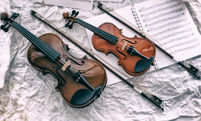 The abstract art design background of two violins put beside blurred sheet music,on grunge surface...