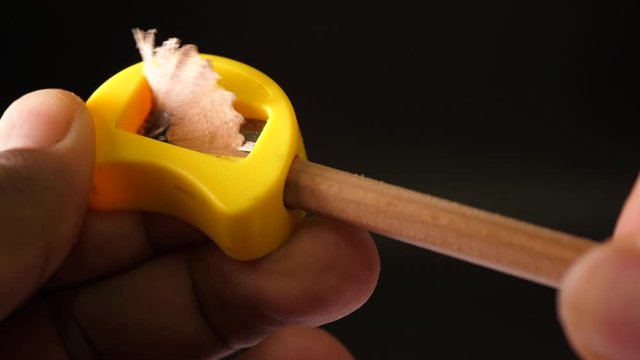 Sharpening a Pencil with a Sharpener on black background