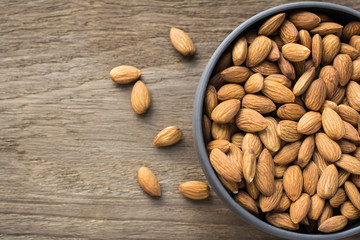Almonds in porcelain bowl on wooden table with copy space.Top view