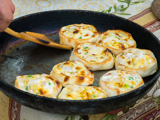 Baker picking up hot mini pies with chicken and cheese at street food festival. Outdoor cooking,...