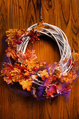  wreath with flowers and autumn leaves on wooden background