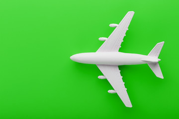 Fototapeta na wymiar White passenger model airplane on a bright green background. Free space for text.