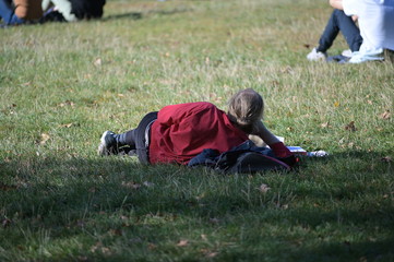 A man with a red shirt lies on a green meadow in Berlin-Germany on a warm and sunny autumn day.