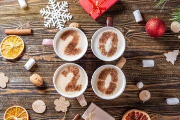 Card with numbers 2020 for New year and Christmas. Cup of coffee with figures on wooden background. Top view. Flat lay