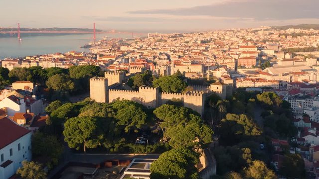 Lisbon, Portugal. Aerial look-down view of the S&atilde;o Jorge Castle (Castelo de S&atilde;o Jorge), with 25 de Abril Bridge on the background at dawn
