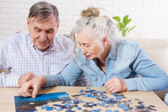 Senior couple solving jigsaw puzzle together at home