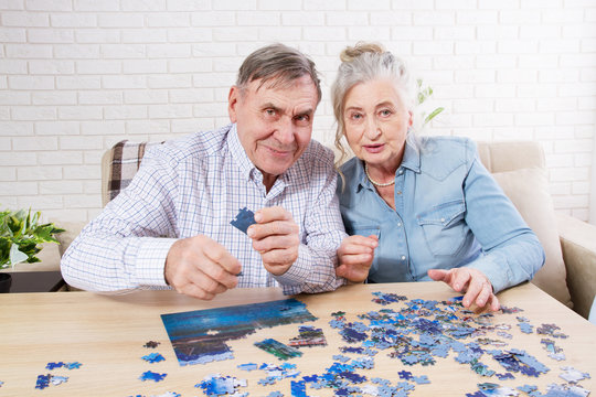 Cute Senior couple solving jigsaw puzzle together at home.