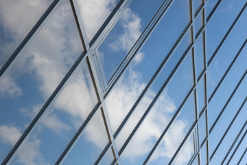 Diagonal view of glass building view with sky reflection, business office facade