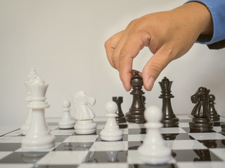 Businessman hand holding chess pieces on board with white background, challenges planning business strategy to success