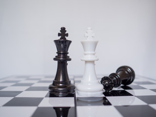 Two king standing on chess board with black queen, challenges planning business strategy to success concept