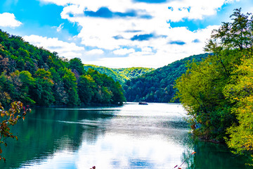 Fototapeta premium Beautiful landscape of clear water, green wood and river boat in autumn, National Park Plitvice Lakes, Croatia