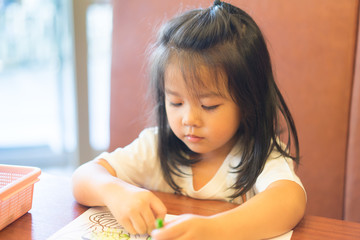 Naklejka premium 4 years old kid girl.Fine motor skills development concept.Little asian girl learning painting drawing in restaurant.