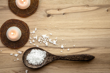 Magnesium Chloride Flakes scattered around brown wooden spoon on natural wood background. For...